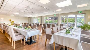 A spacious indoor dining area with multiple tables and chairs, large windows, and a clean, modern design.