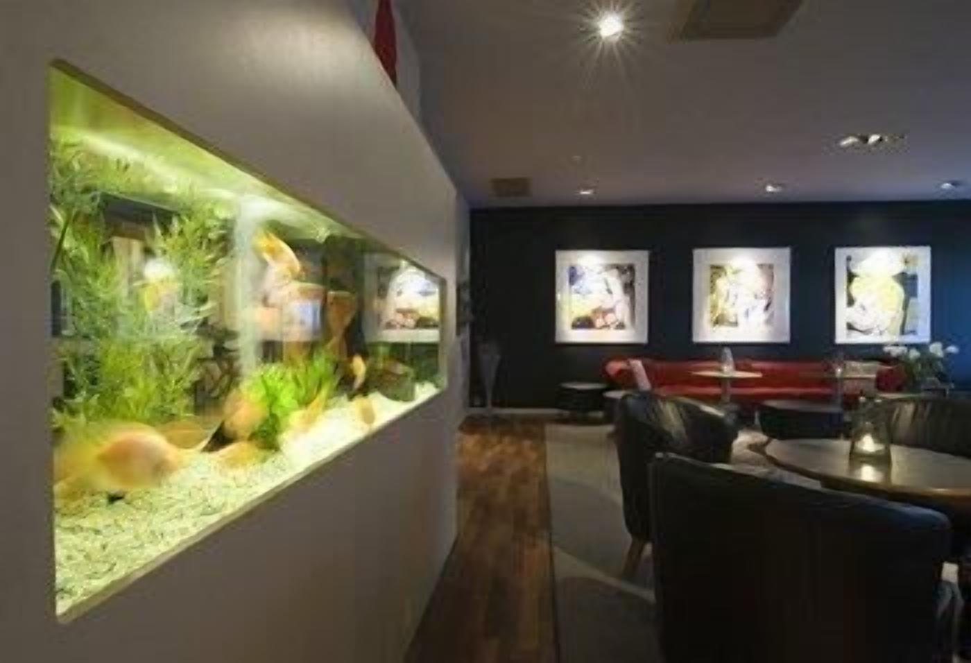 A modern interior with a fish tank, seating area, and artwork on the walls.