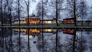A hotel with a reflection in a calm body of water, surrounded by trees. - Best Western Hotel Norra Vattern (Askersund)