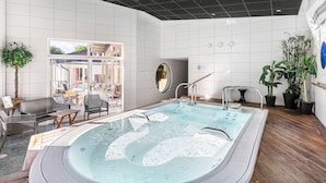 A modern indoor pool area with a large hot tub, seating area, and potted plants. - Best Western Hotel Norra Vattern (Askersund)