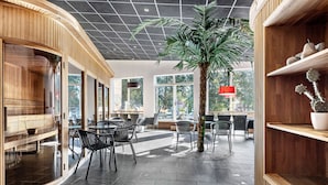 A modern interior with curved wooden walls, a central palm tree, and a seating area with tables and chairs. - Best Western Hotel Norra Vattern (Askersund)