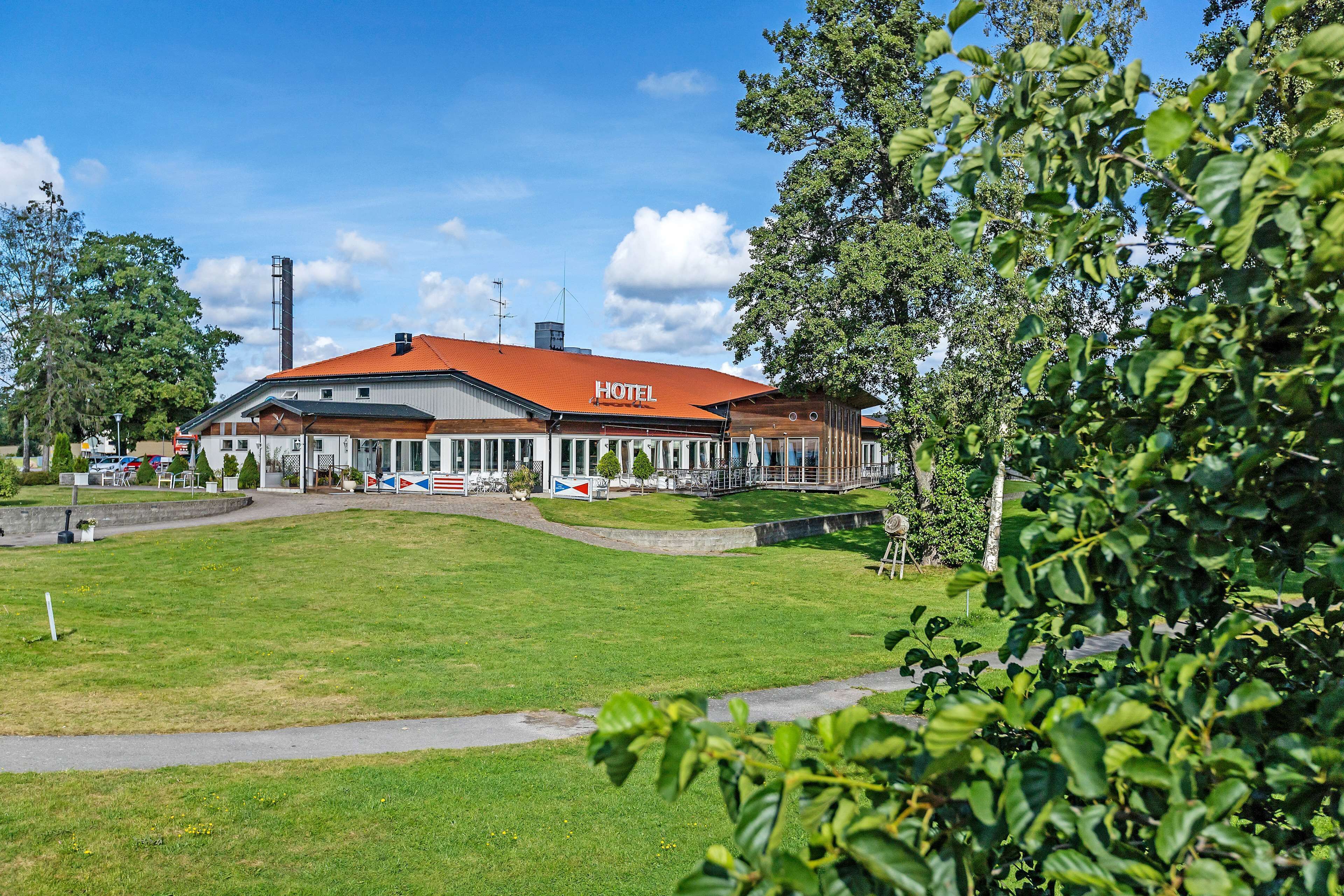 A hotel with a red roof, a covered outdoor area, and a grassy lawn.