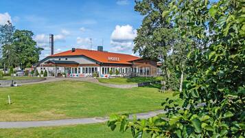 A hotel with a red roof, a covered outdoor area, and a grassy lawn.