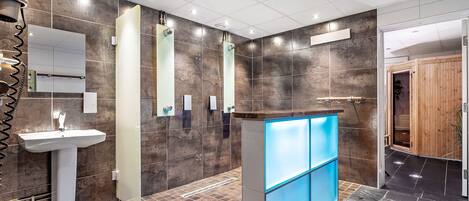 A modern bathroom with a pedestal sink, a mirror, and a blue-lit vanity.