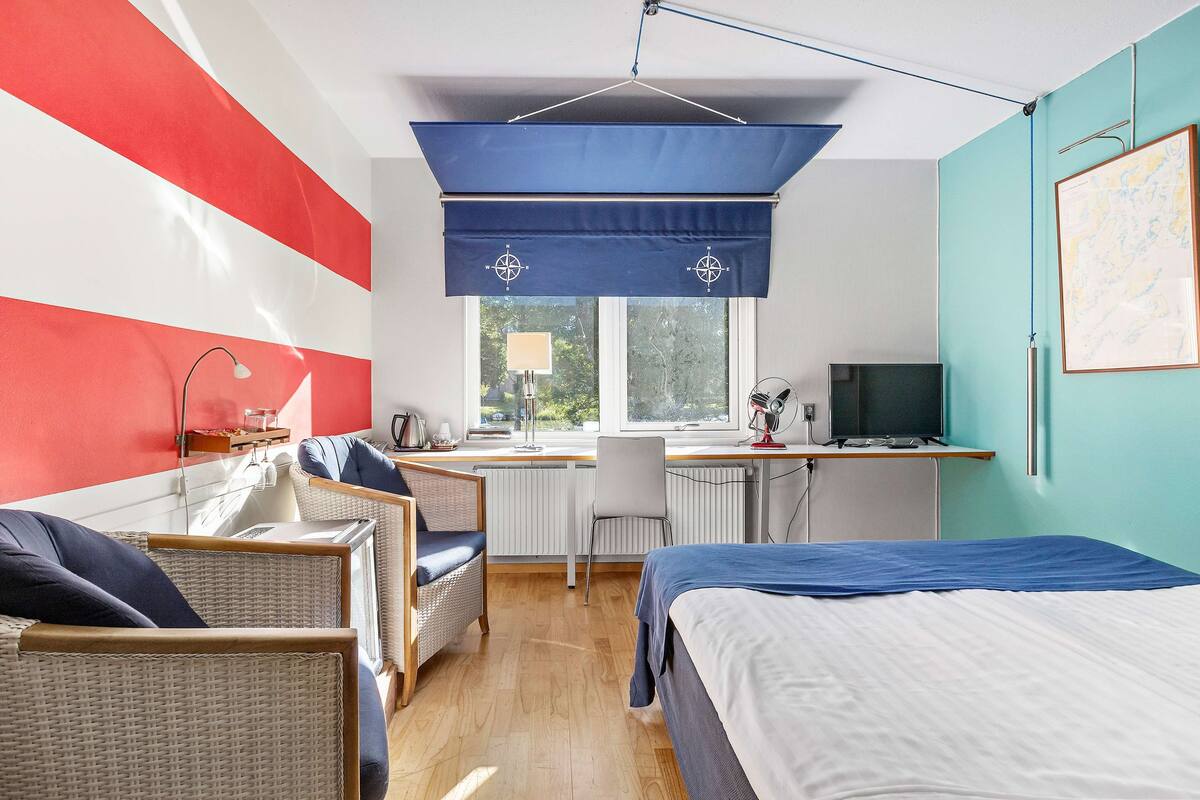 Una habitación con una cama, un escritorio, una silla y una ventana.
