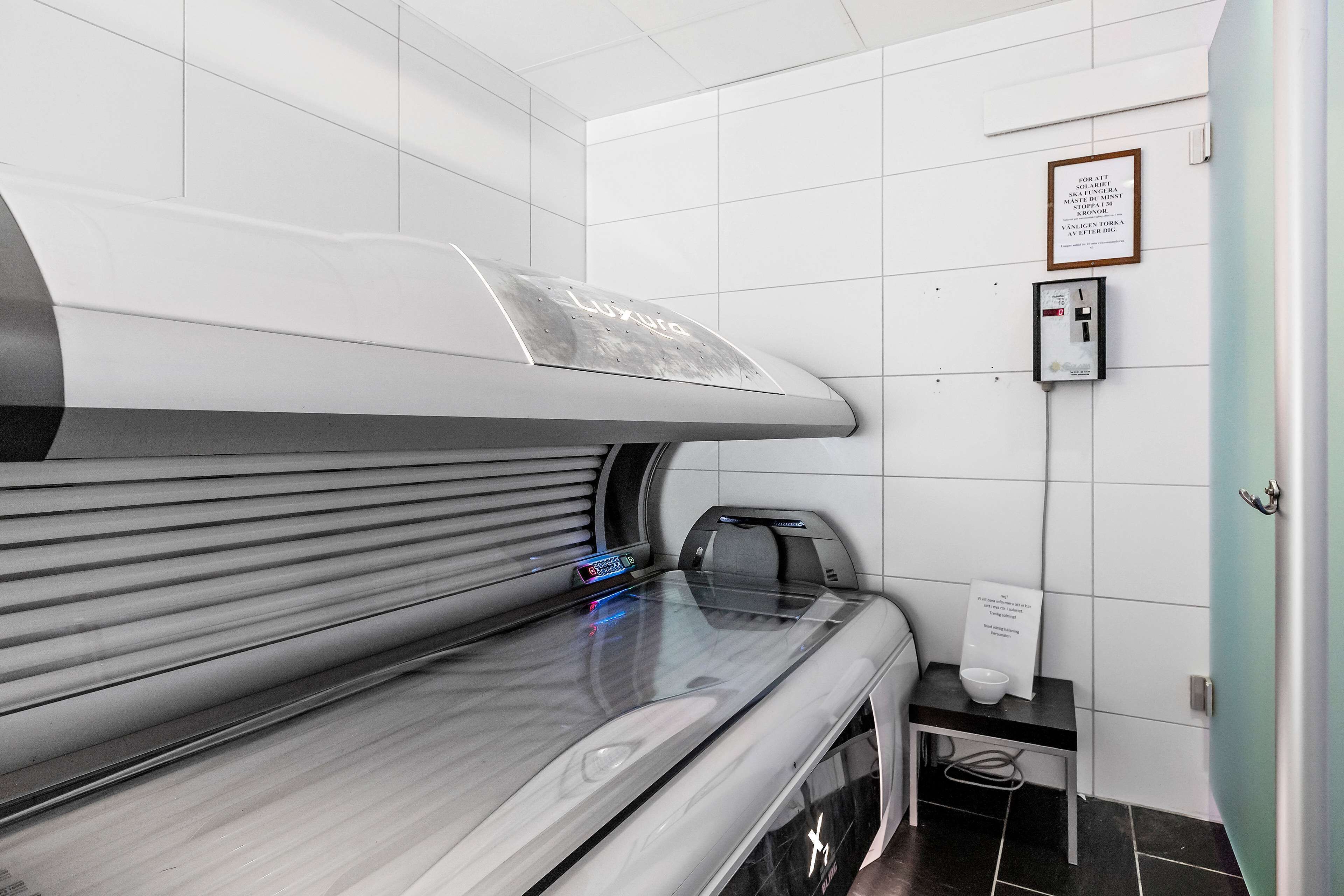 Une salle de spa moderne, équipée d’une grande table de massage, d’une petite table avec un récipient, et d’une affiche encadrée accrochée au mur.