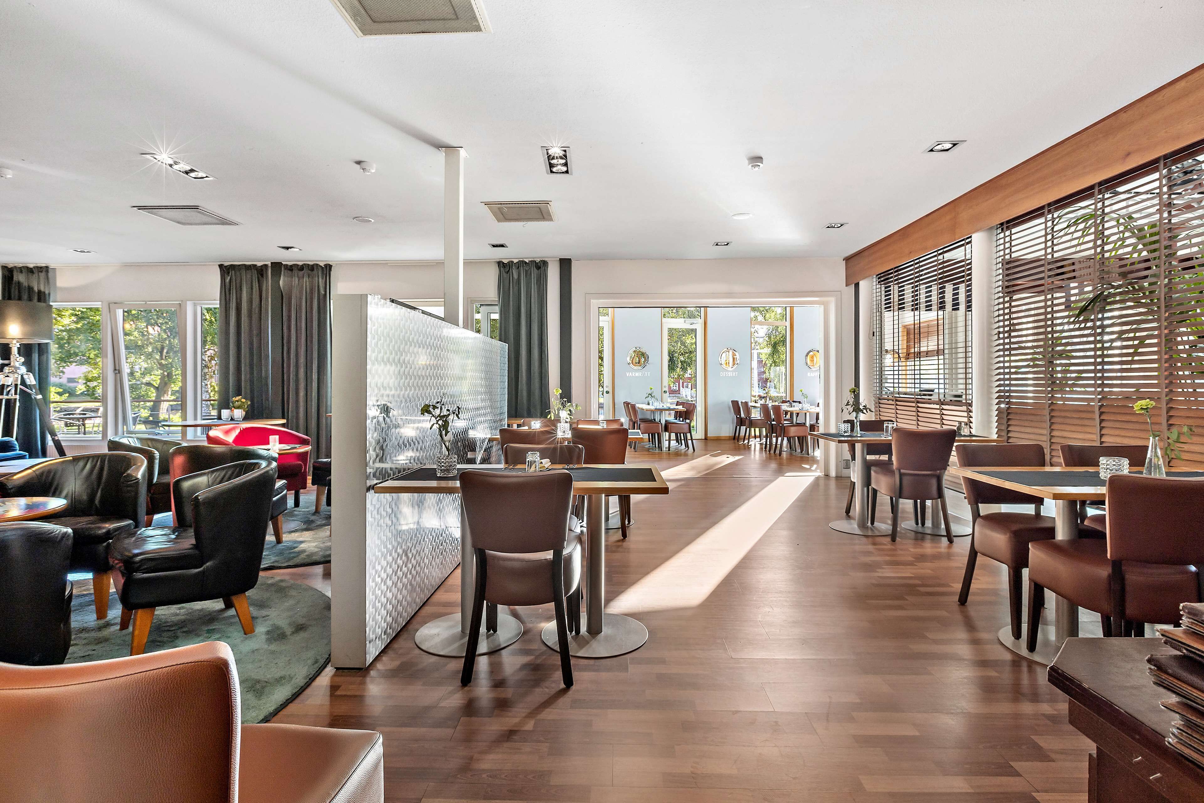 A spacious restaurant with wooden flooring, leather chairs, and a central bar area.