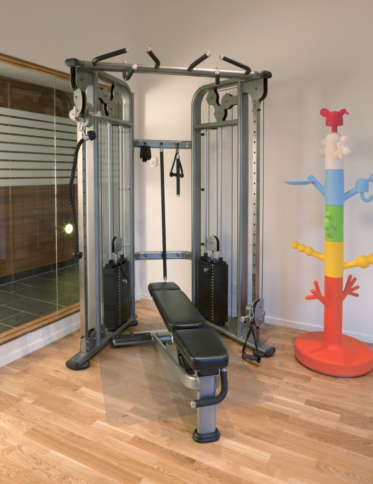 A gym with a bench, weight machines, and a colorful children's play structure.