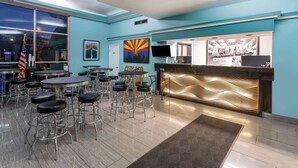 A bar area with multiple stools and tables, a reception desk, and a large window with an American flag. - Super 8 by Wyndham Conference Center NAU/Downtown (Flagstaff)