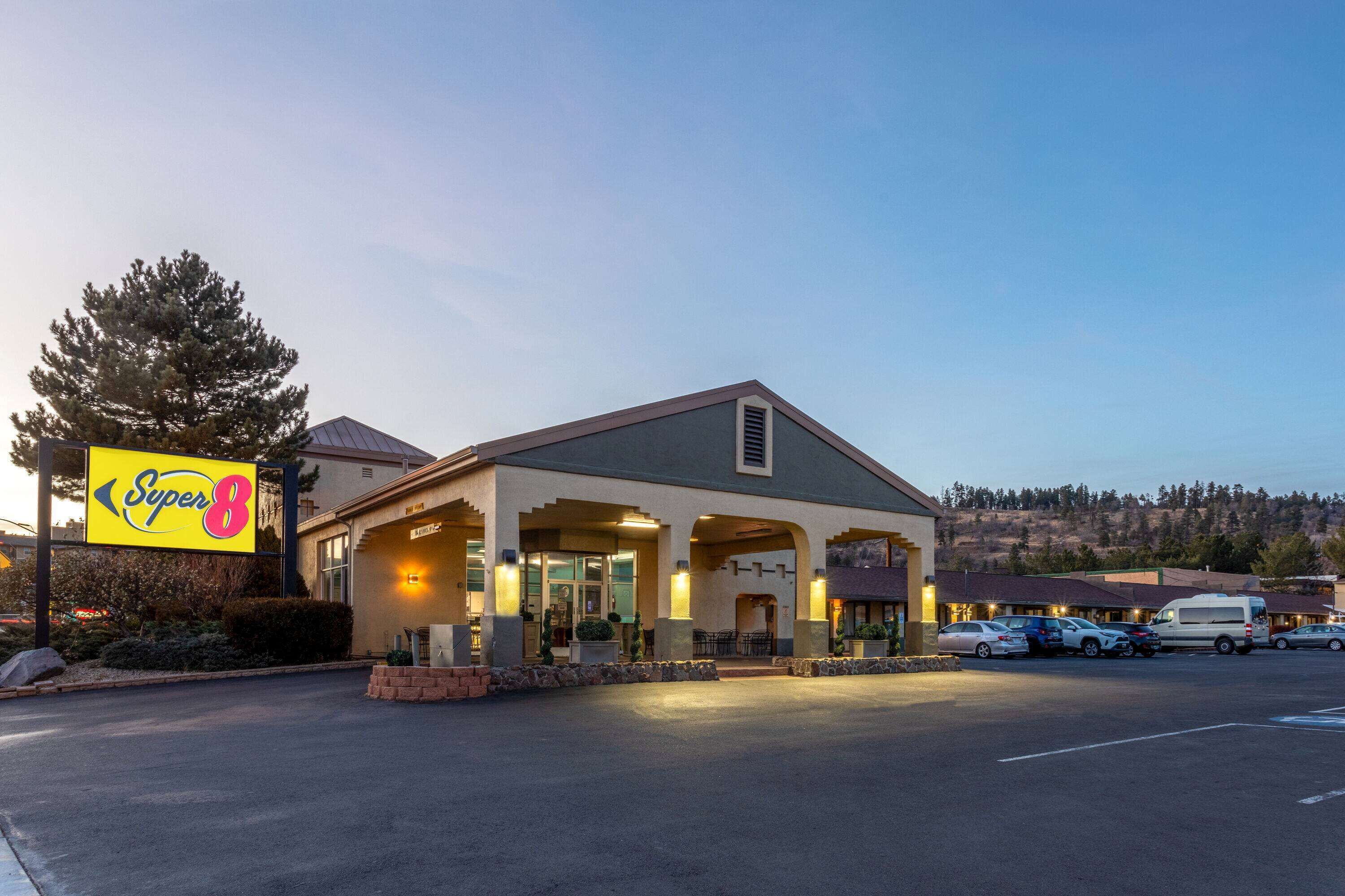 Un motel Super 8 con estacionamiento, un letrero grande y un edificio de techo inclinado.