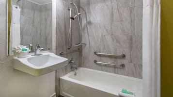 Casa de banho com lavatório branco, banheira e chuveiro com barras de apoio.
