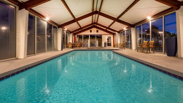 A swimming pool with a covered area, glass doors, and seating. - Super 8 by Wyndham Conference Center NAU/Downtown (Flagstaff)