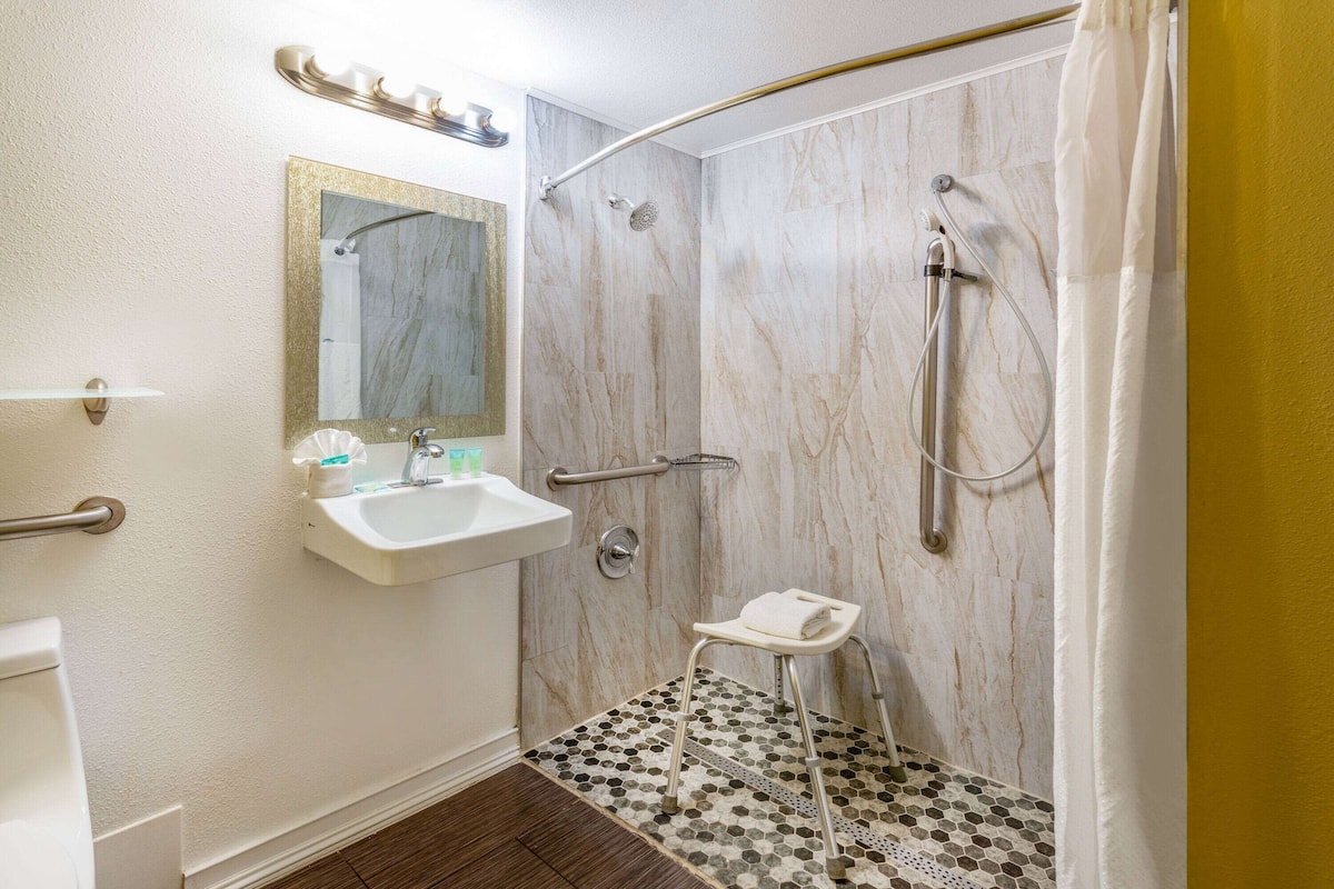 Une salle de bain équipée d’un lavabo, d’un miroir, d’une douche et d’un petit marchepied.