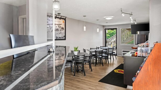 A modern kitchen with a marble countertop, black chairs, and a dining area with a black rug.