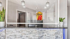 A modern kitchen with a marble backsplash, a glass countertop, and pendant lighting.