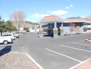 A parking lot with a building featuring a red roof and stone pillars. - Econo lodge Flagstaff East I-40 (Flagstaff)