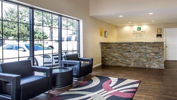 A reception area with a stone wall, a reception desk, and a seating area with chairs and a coffee table. - Econo lodge Flagstaff East I-40 (Flagstaff)