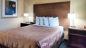 A hotel room with a large bed, two bedside tables with lamps, a framed picture on the wall, and a wooden headboard. - Econo lodge Flagstaff East I-40 (Flagstaff)
