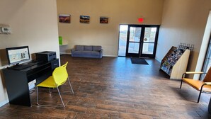 A reception area with a computer desk, a couch, and a chair. There are paintings on the wall and a door leading outside. - Econo lodge Flagstaff East I-40 (Flagstaff)