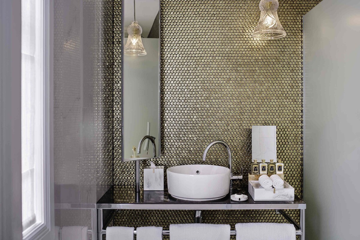 A modern bathroom with a large mirror, a white sink, and two pendant lights.