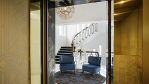 A modern interior with a spiral staircase, two blue armchairs, and a patterned rug. - Fable Auckland, MGallery (Auckland)