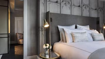 Een hotelkamer met een groot bed, een nachtkastje met een lamp, een stoel en een vaas met bloemen.