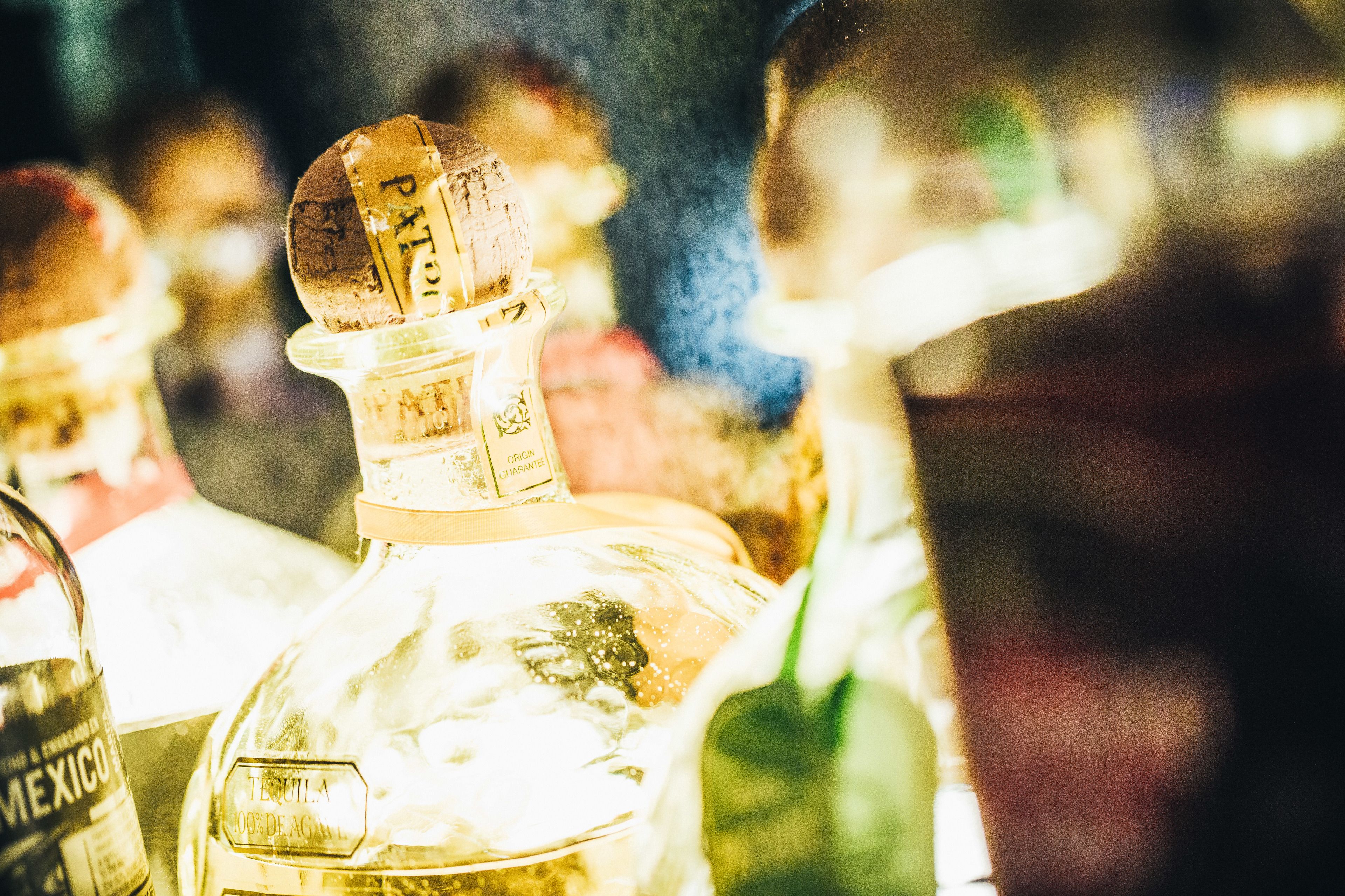 Tequila-pullo, jossa on korkki ja etiketti, ja sen ympärillä on muita pulloja.