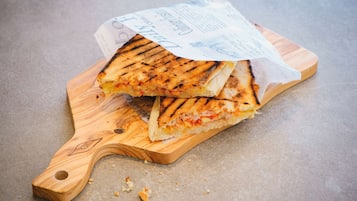 A grilled sandwich on a wooden cutting board with a receipt on top.