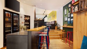 Een moderne keuken met een bar, houten krukken en een trap naar een woongedeelte.