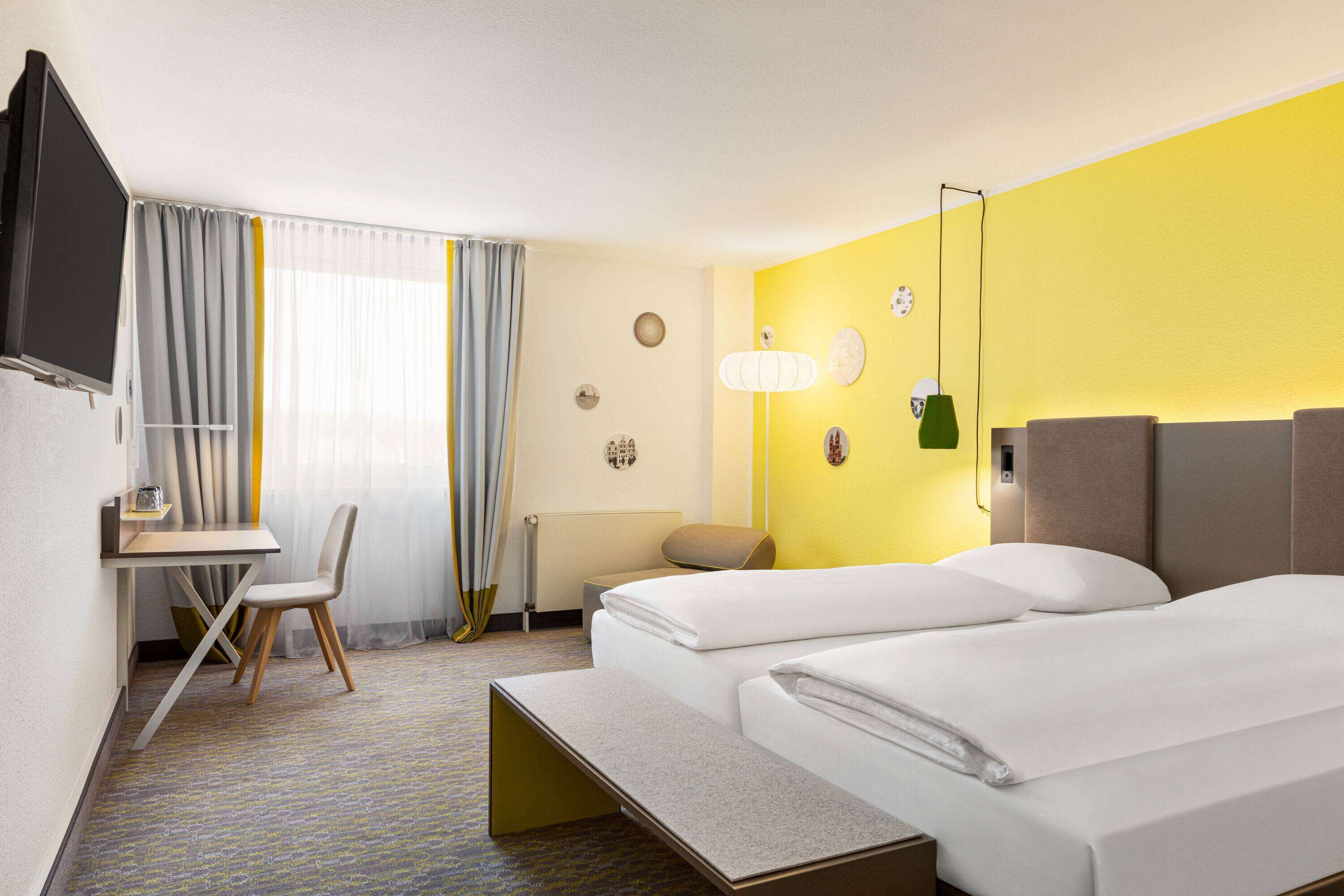 Una habitación de hotel con cama, escritorio, silla y televisor.