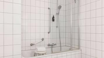 A modern bathroom with a glass-enclosed shower, a white bathtub, and a small stool with a towel.