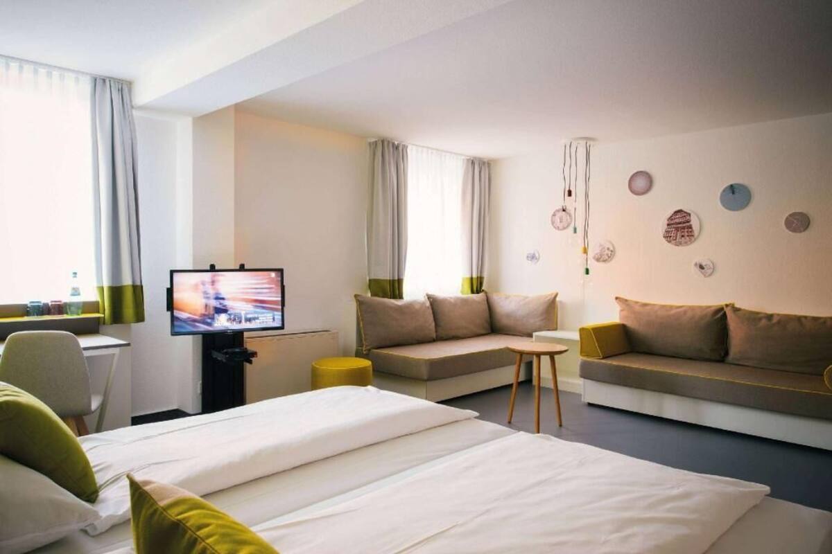 Une chambre d’hôtel avec deux lits, un canapé, une télévision et une petite table.