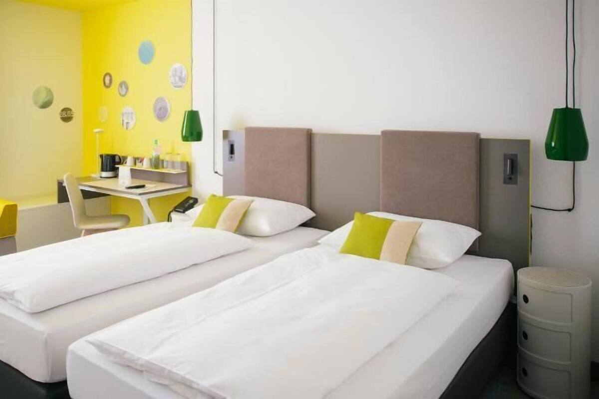 Une chambre d’hôtel avec deux lits, un bureau et une chaise.