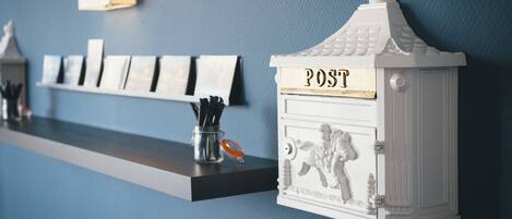 Una estantería con postales y un buzón decorativo que dice "POST".