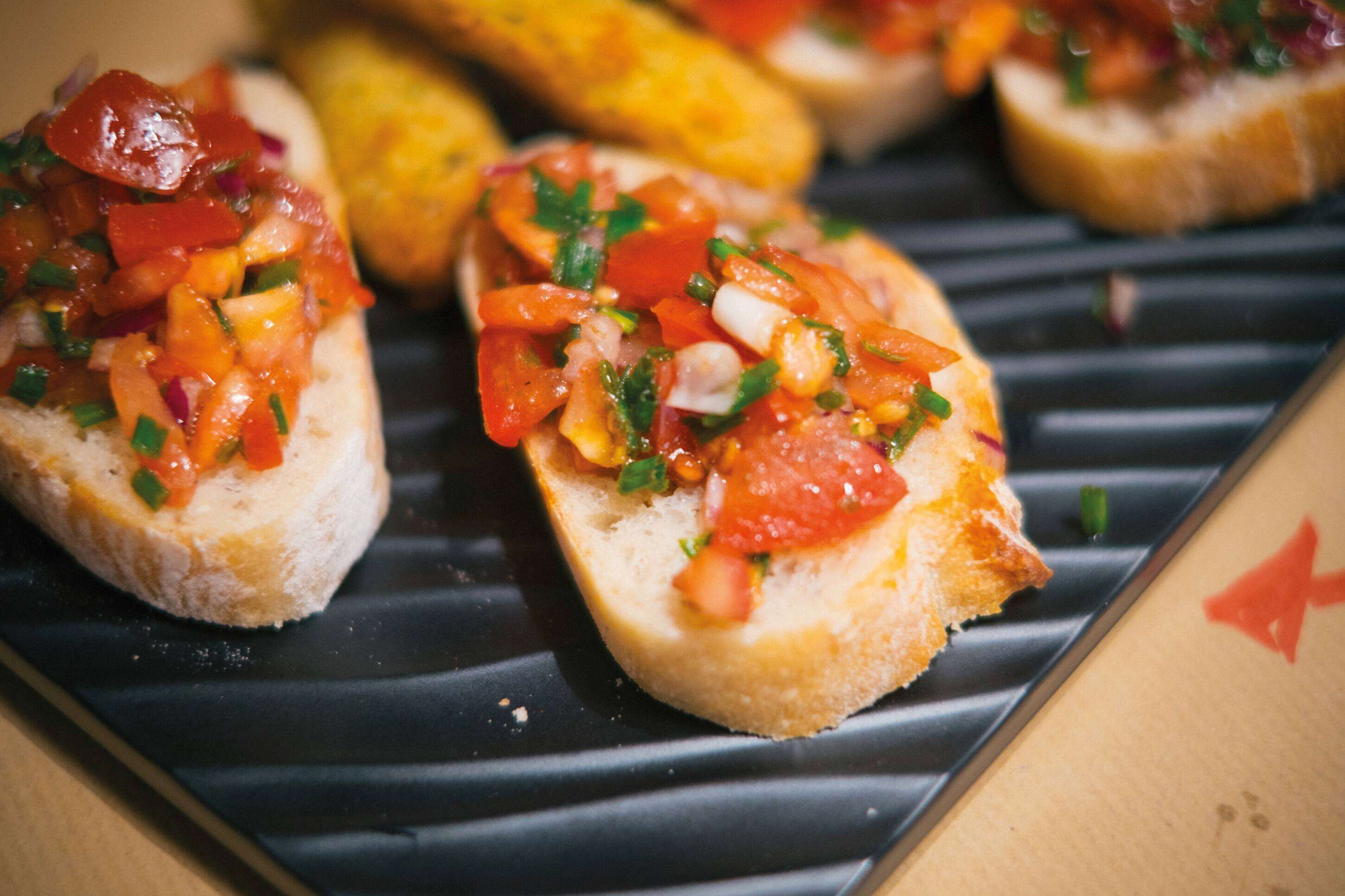 A plate with bruschetta topped with diced tomatoes and herbs.