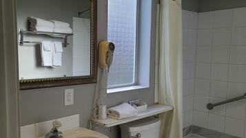 A bathroom with a sink, toilet, and bathtub. There is a window above the toilet and a towel rack with towels.