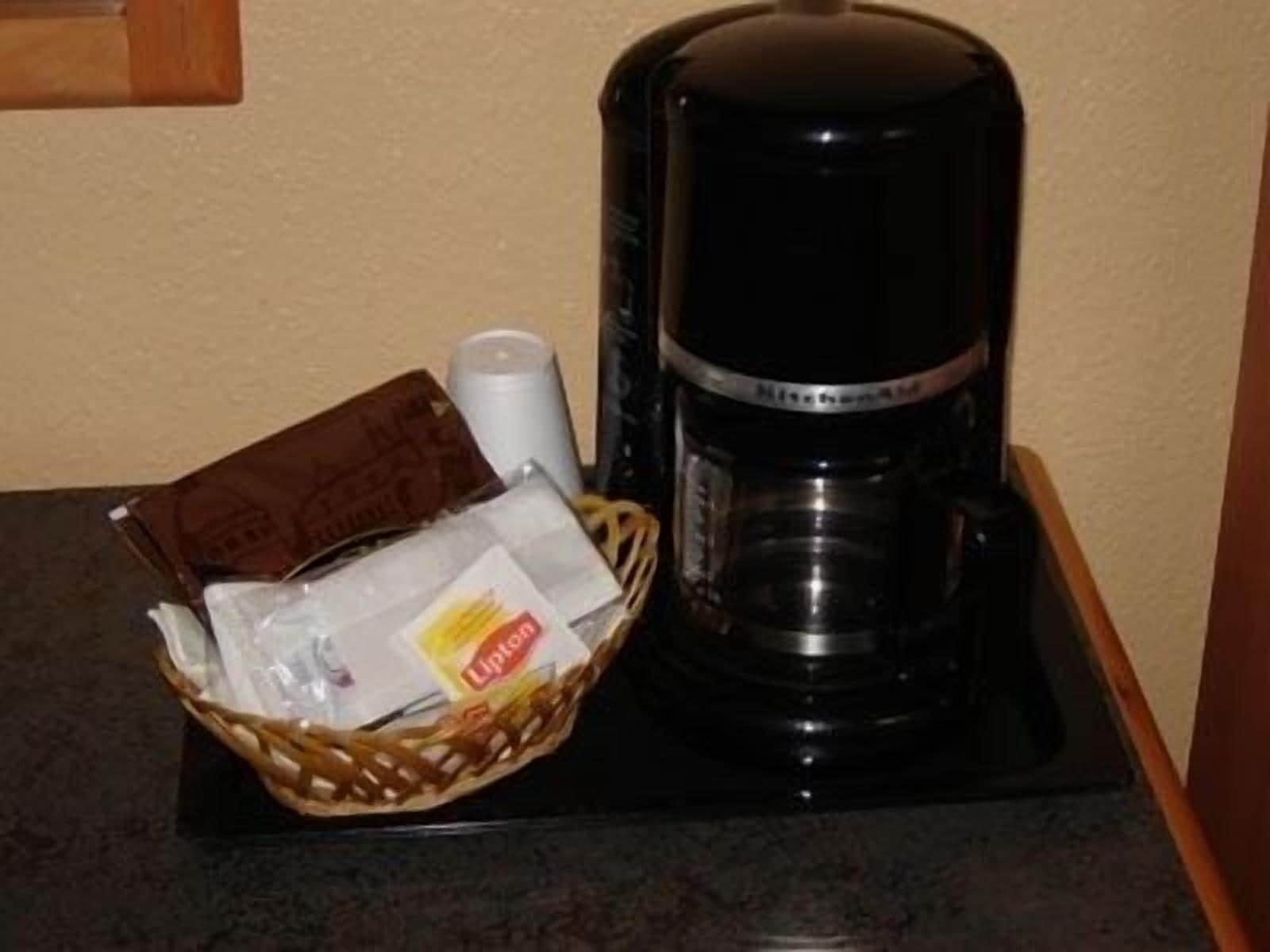 A coffee maker and a basket of items on a countertop.