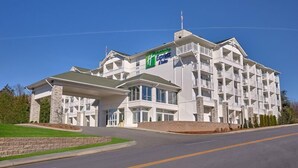 A multi-story hotel with a prominent green and white sign, featuring a modern architectural design with a flat roof and large windows. - Holiday Inn Express and Suites Pigeon Forge Sevierville by IHG (Sevierville)