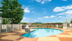 Un espace piscine équipé d’un élévateur pour faciliter l’accès à la piscine, de chaises et offrant une vue sur les montagnes.