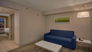 Un salon moderne avec un canapé bleu, une table basse blanche et un tableau accroché au mur.