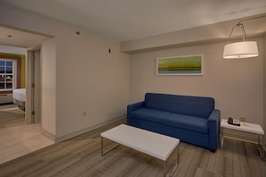 A modern living room with a blue sofa, a white coffee table, and a painting on the wall. - Holiday Inn Express and Suites Pigeon Forge Sevierville by IHG (Sevierville)