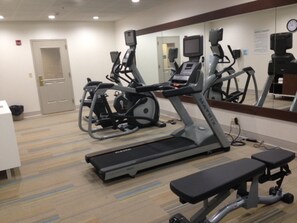 A gym with treadmills, an elliptical, and a bench.