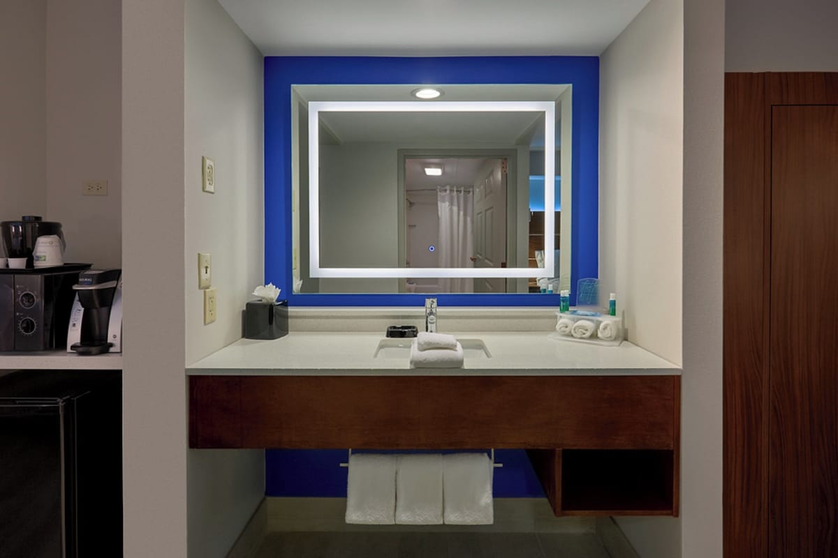 A bathroom with a white sink, a mirror, a towel rack, and a shower curtain.