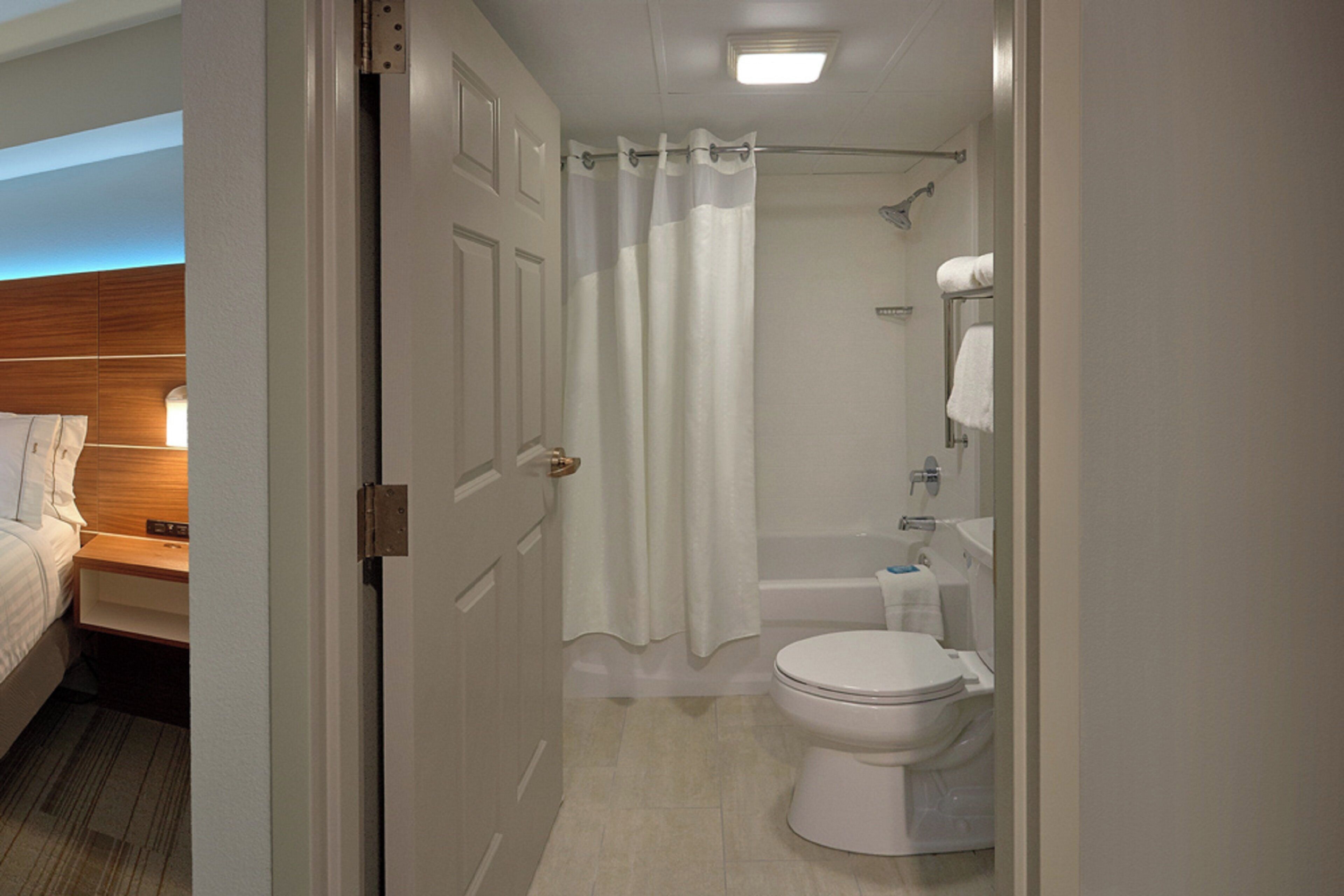 A bathroom with a toilet, a bathtub, and a shower curtain.