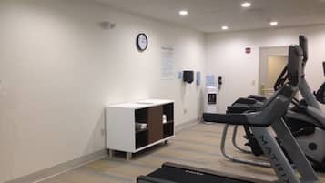 A fitness room with treadmills, a water dispenser, and a clock on the wall.