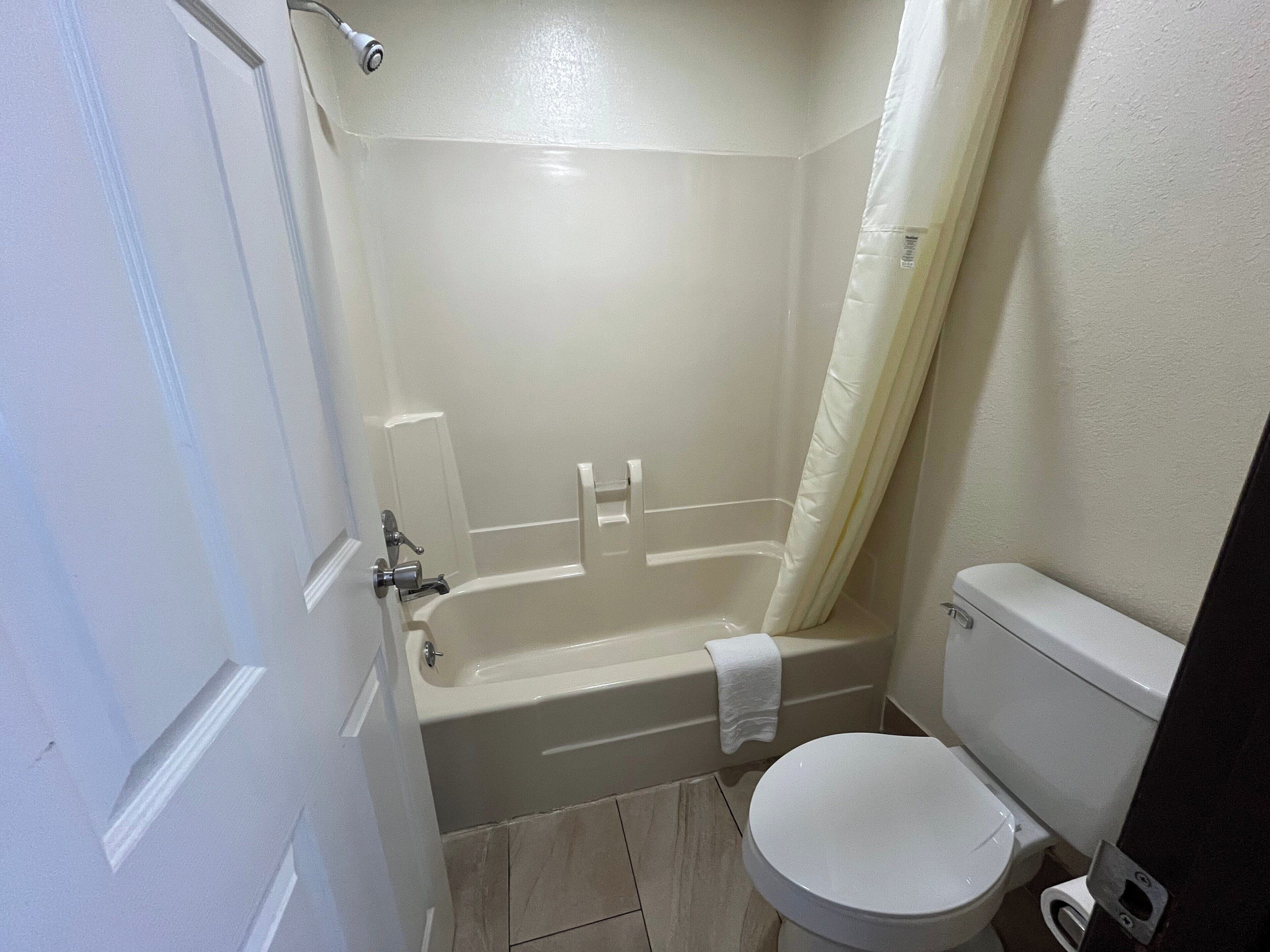 A bathroom with a bathtub, toilet, and shower curtain.