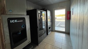 A hallway with two ice dispensers, a fire extinguisher, and a door leading to a parking lot. - Budget Inn (Nassawadox)