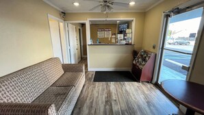 A hotel lobby with a reception desk, a sofa, and a view of the street. - Budget Inn (Nassawadox)
