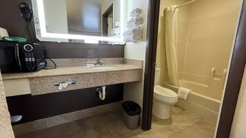 Un baño con encimera de granito, lavabo, inodoro, cortina de ducha y cubo de basura.