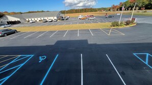 A parking lot with marked handicapped spaces, a building with a garage, and a clear sky. - Budget Inn (Nassawadox)